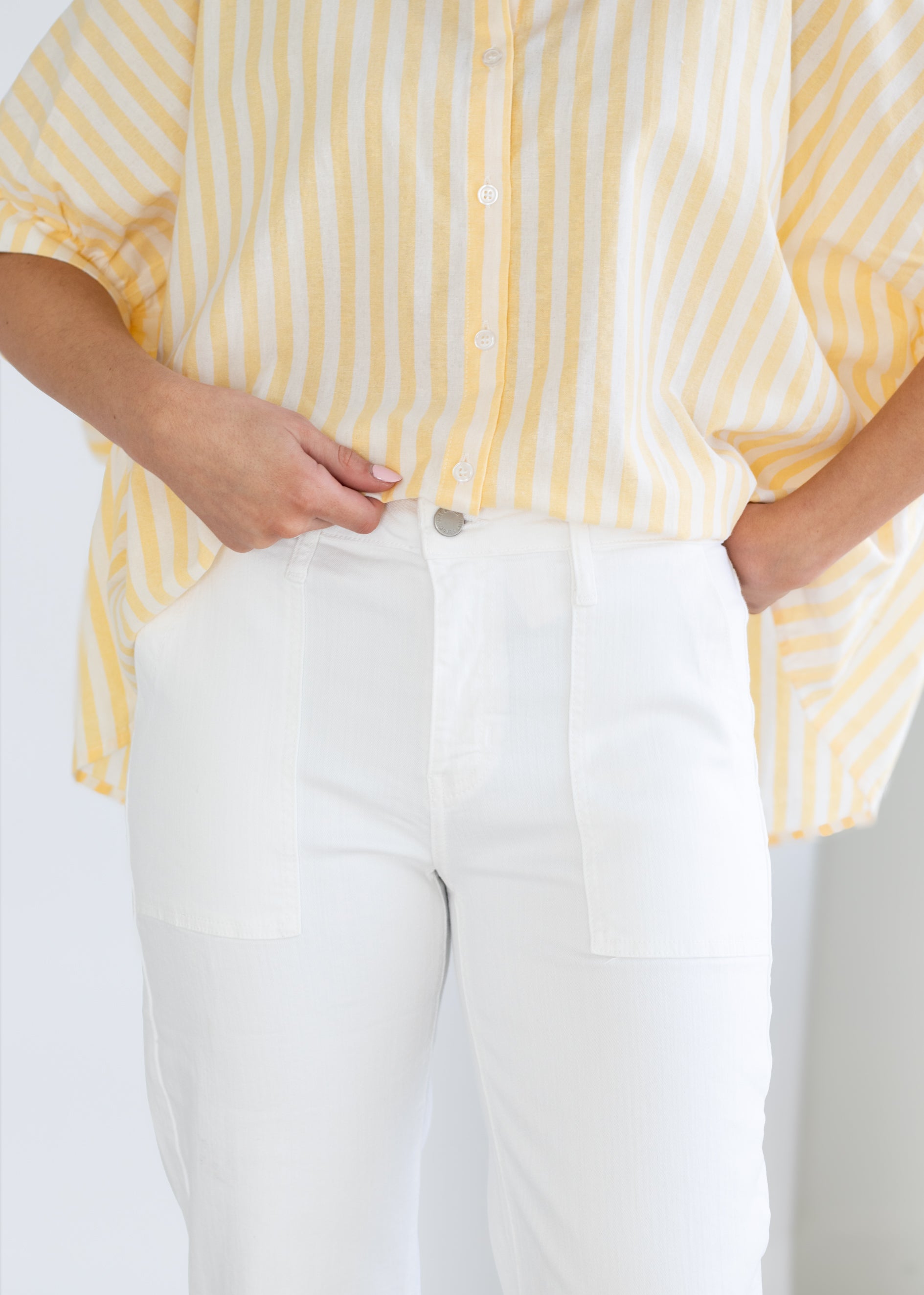 Person wearing a yellow and white striped shirt with white pants on a plain background
