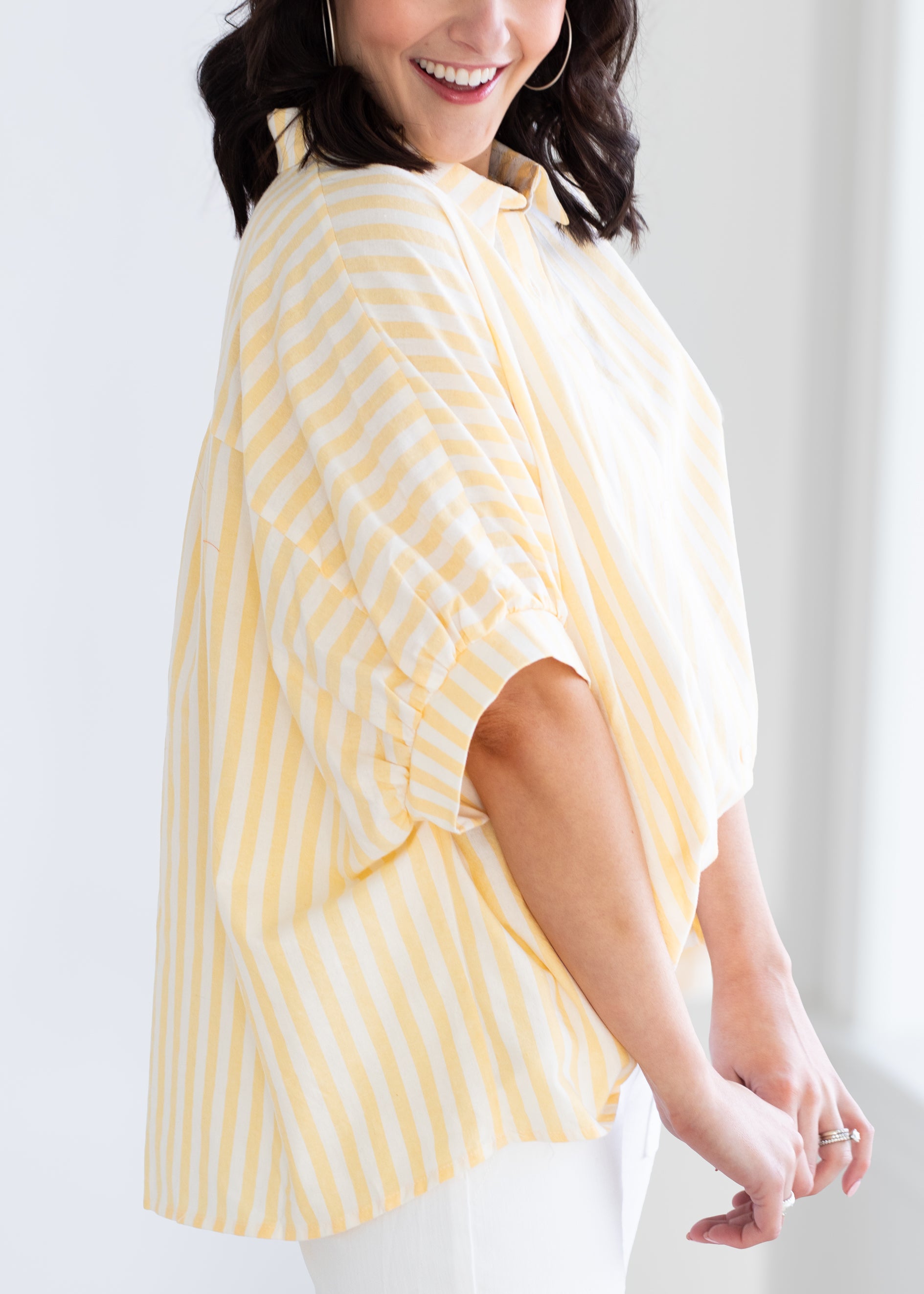 Woman wearing a yellow and white striped shirt against a plain background