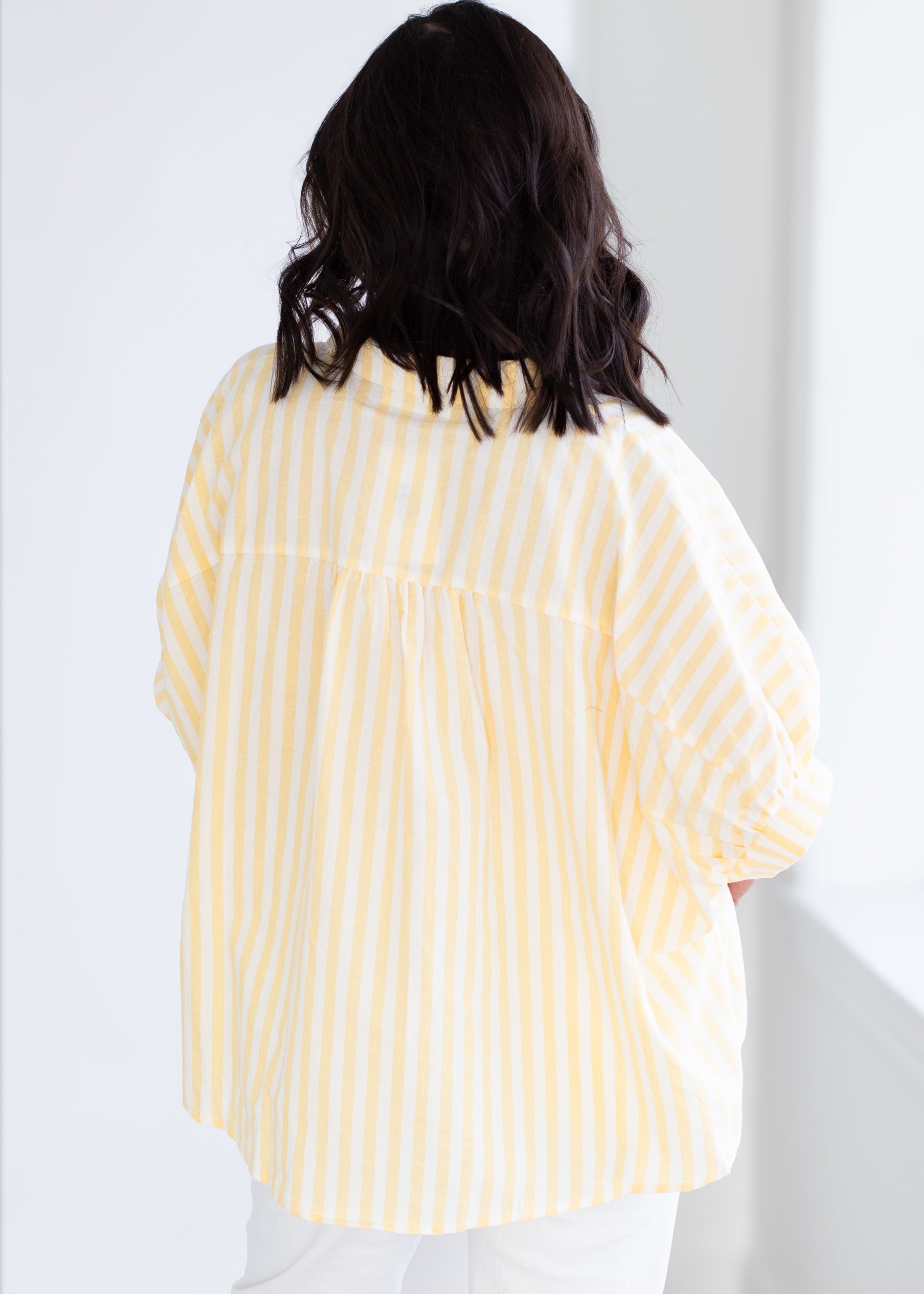 Person wearing a yellow striped shirt against a white background