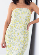 Woman wearing a strapless floral dress with yellow and green pattern on a white background