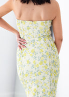 Woman wearing a strapless floral dress with yellow flowers on a white background