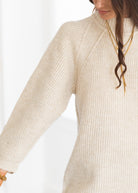 Close-up of a person wearing a beige ribbed sweater on a white background