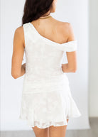 Woman wearing a white one-shoulder dress against a plain background