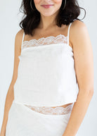 Woman wearing a white lace top against a plain background