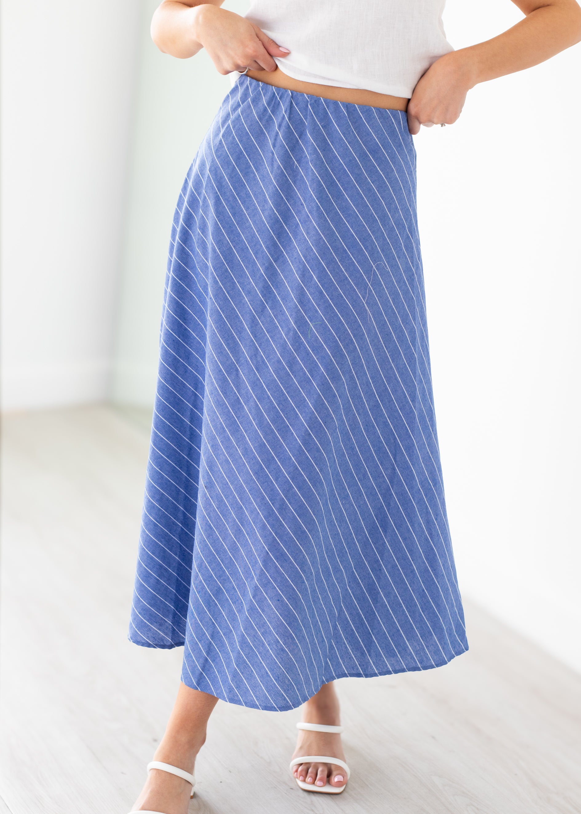 Person wearing a blue striped skirt on a white background