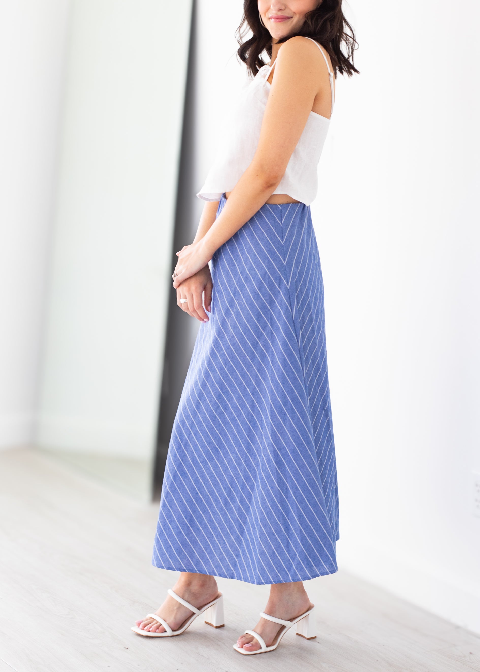 Woman wearing a white top and blue striped skirt on a white background