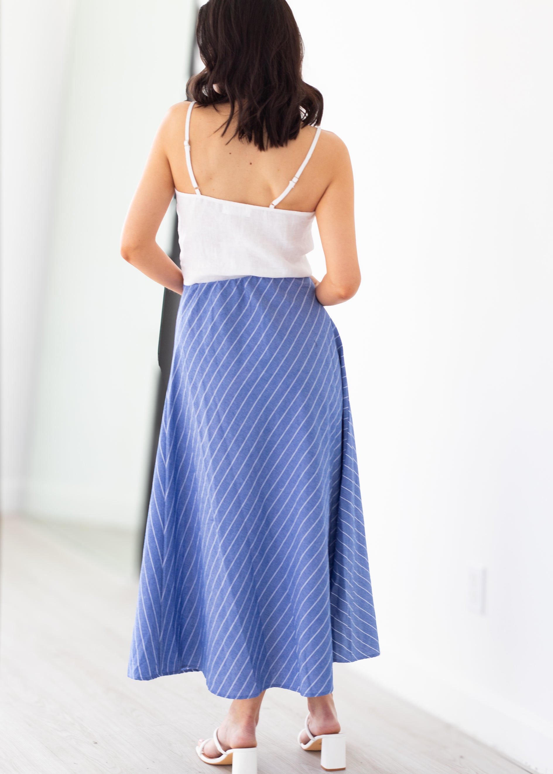 Woman wearing a white top and blue skirt against a white background
