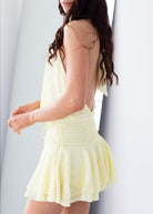 Woman wearing a light yellow dress with a plain background