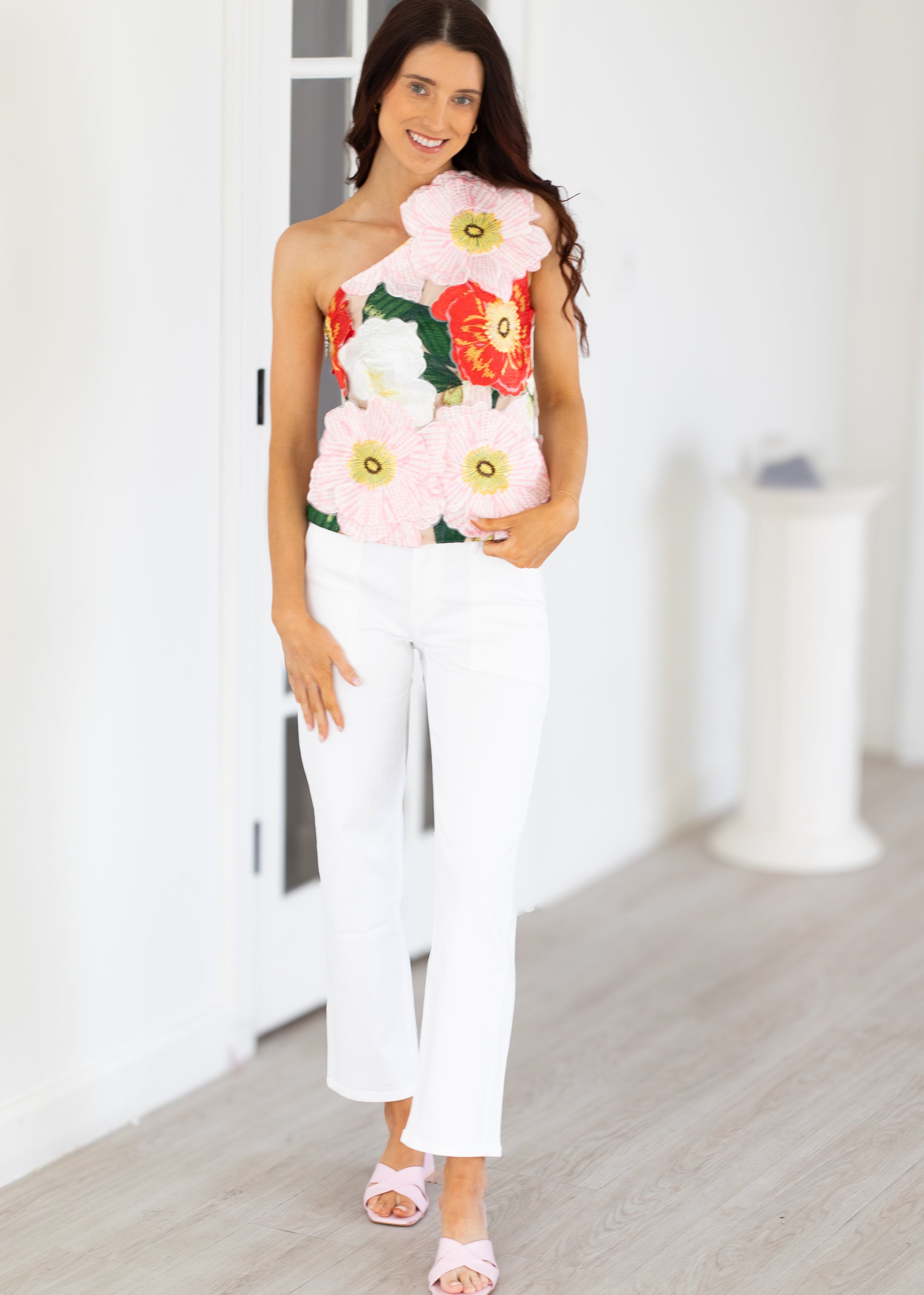 Woman wearing a strapless floral dress with white pants indoors.