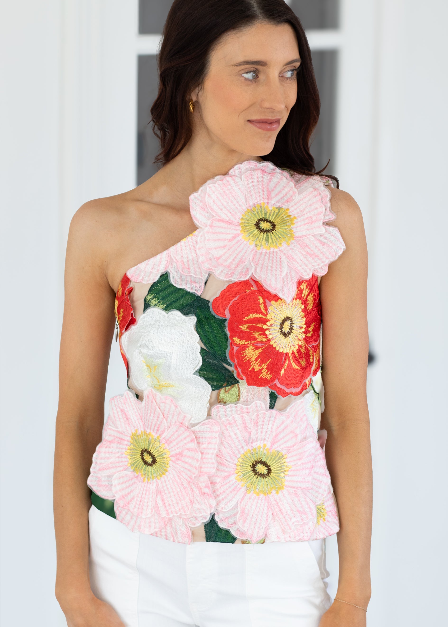 Woman wearing a floral one-shoulder top against a white background