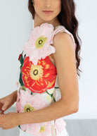 Woman wearing a sleeveless top with floral designs on a plain background
