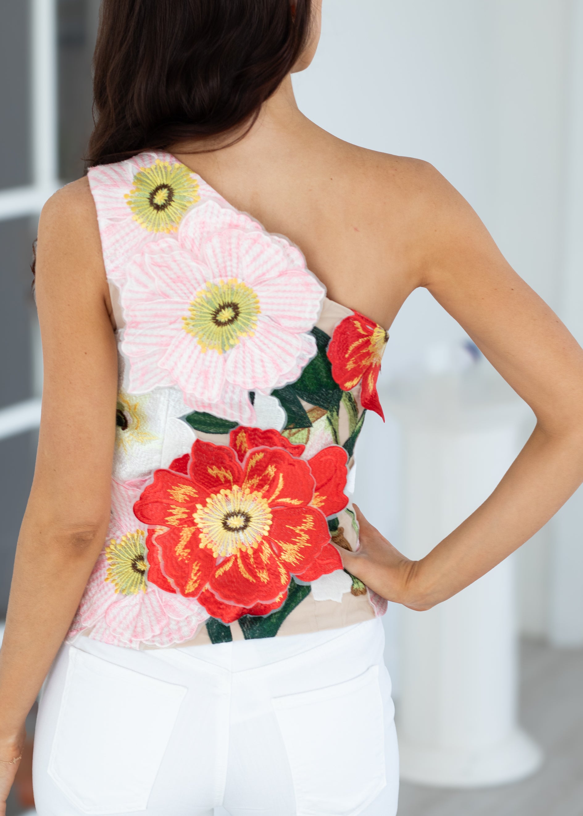 Woman wearing a floral one-shoulder top with a blurred background