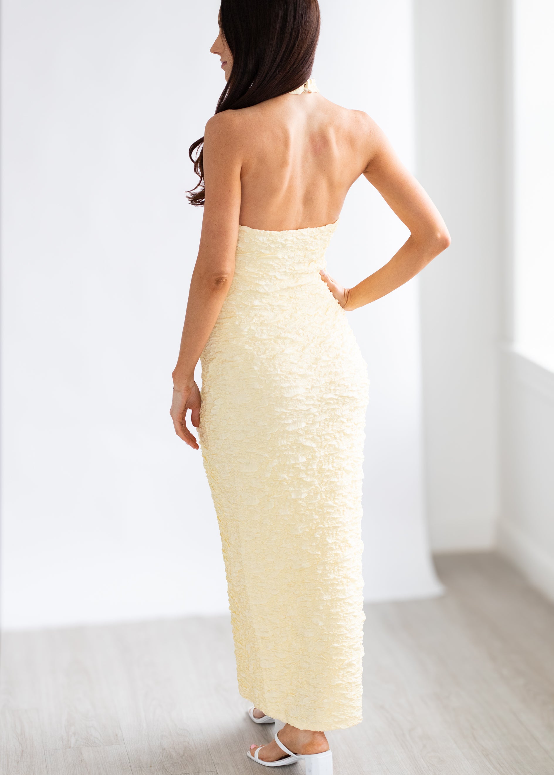 Woman wearing a strapless yellow dress in a minimal white room