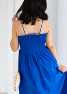 Woman wearing a blue dress with thin straps against a white background