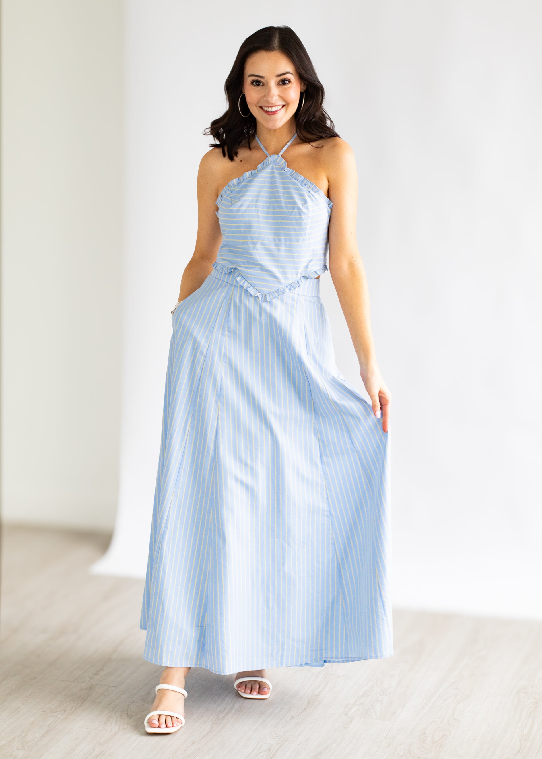 Woman wearing a light blue striped dress against a white background