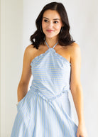 Woman wearing a light blue and white striped dress against a plain background