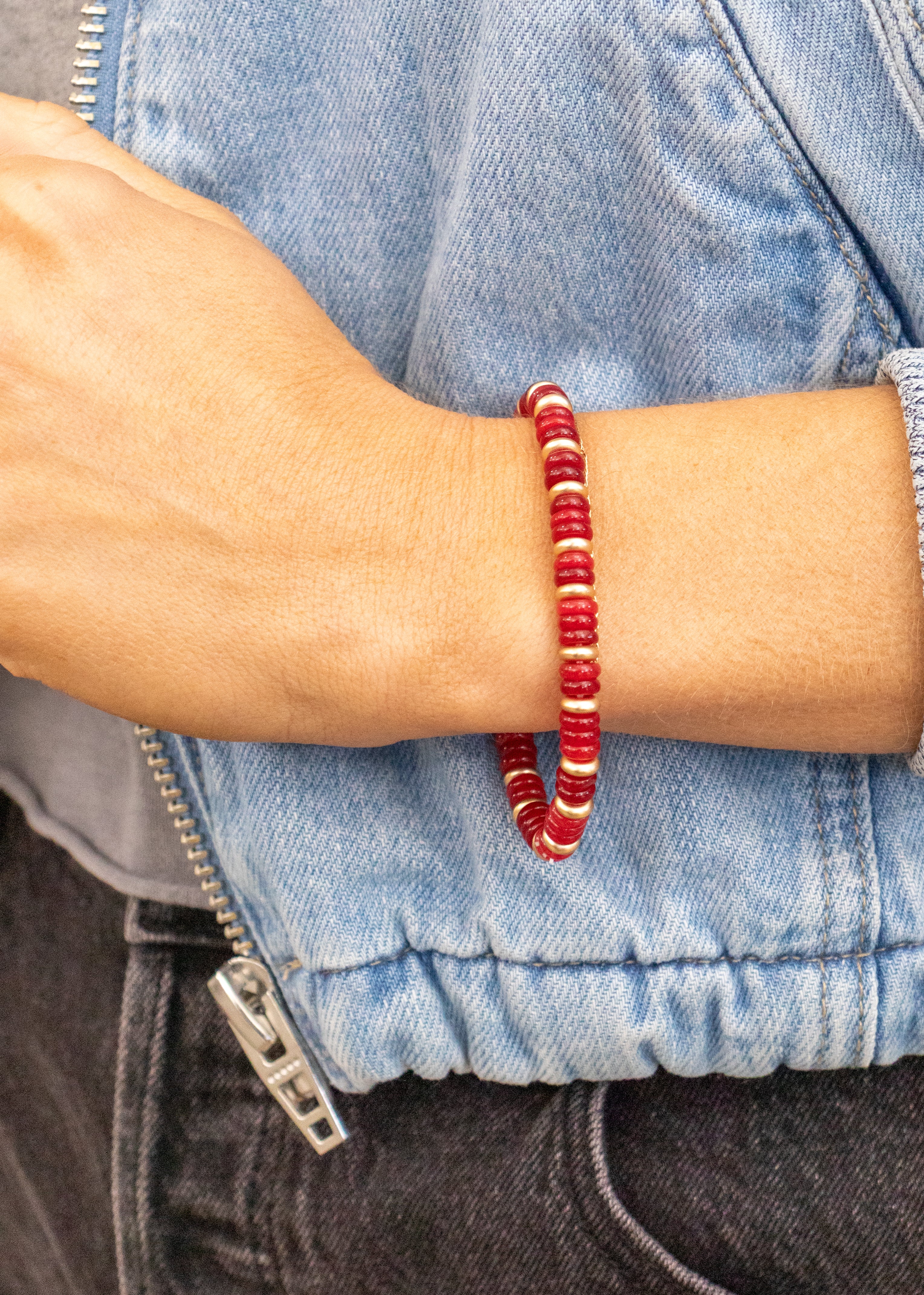 Red beaded bracelet on a wrist with a denim jacket