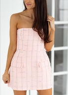 Woman wearing a pink strapless dress with a white background