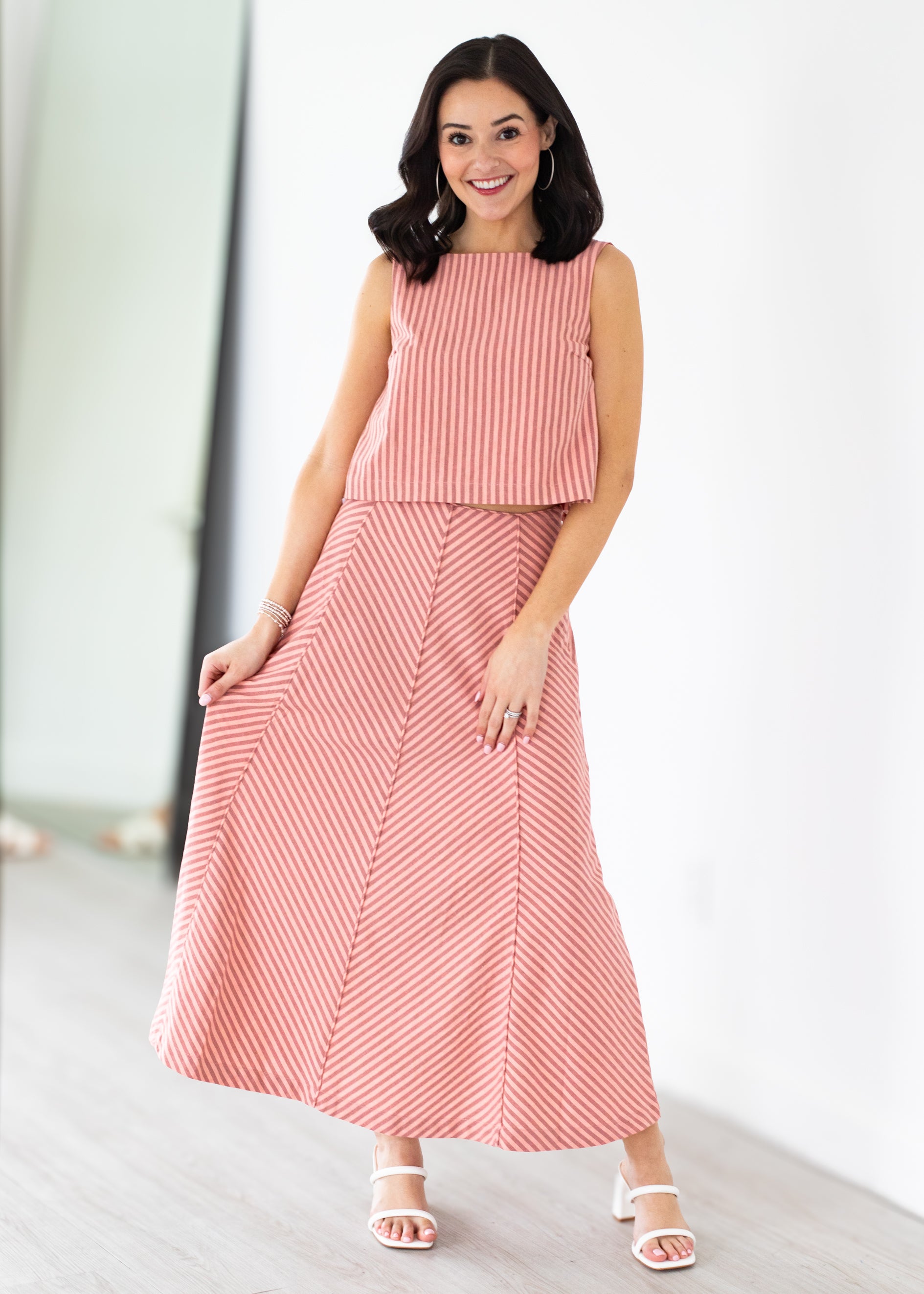 Woman wearing a pink and white striped dress on a white background
