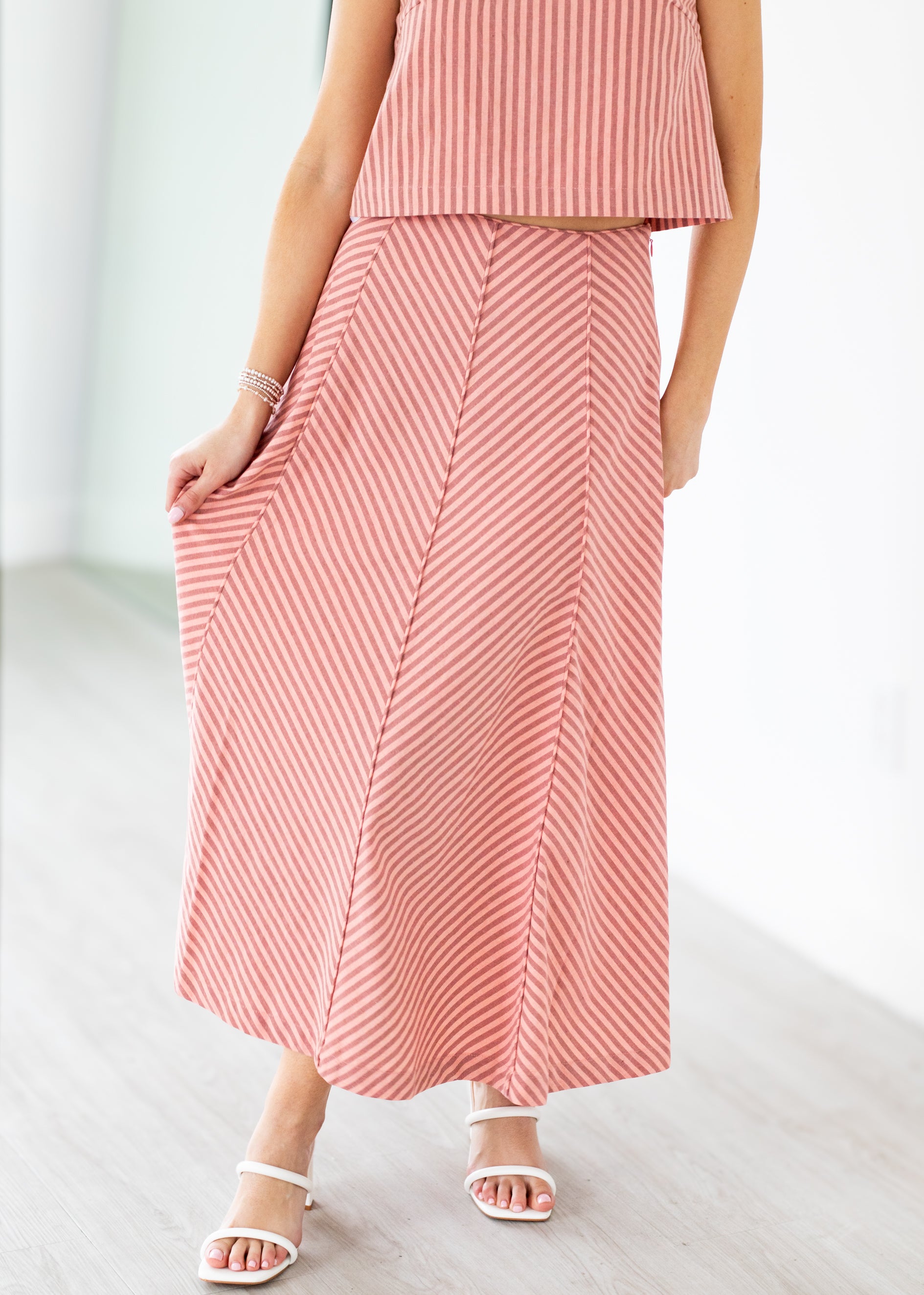 Person wearing a pink and white striped outfit on a light background