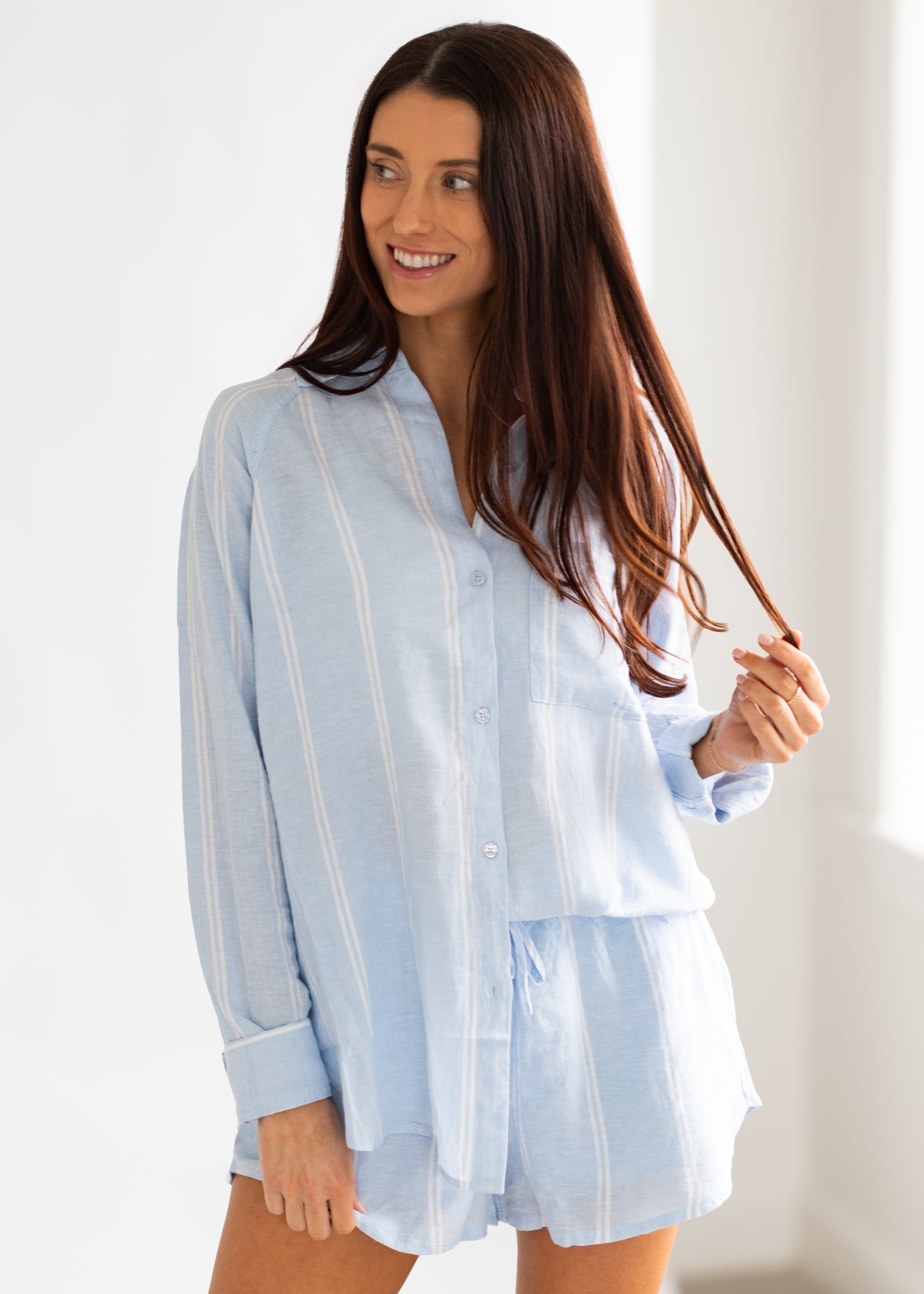 Woman wearing a light blue striped shirt against a white background