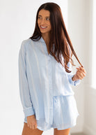 Woman wearing a light blue striped shirt against a white background