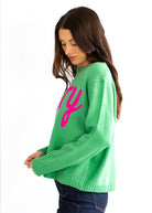 Woman wearing a green sweater with pink text on a white background