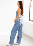 Woman wearing a denim jumpsuit in a bright room