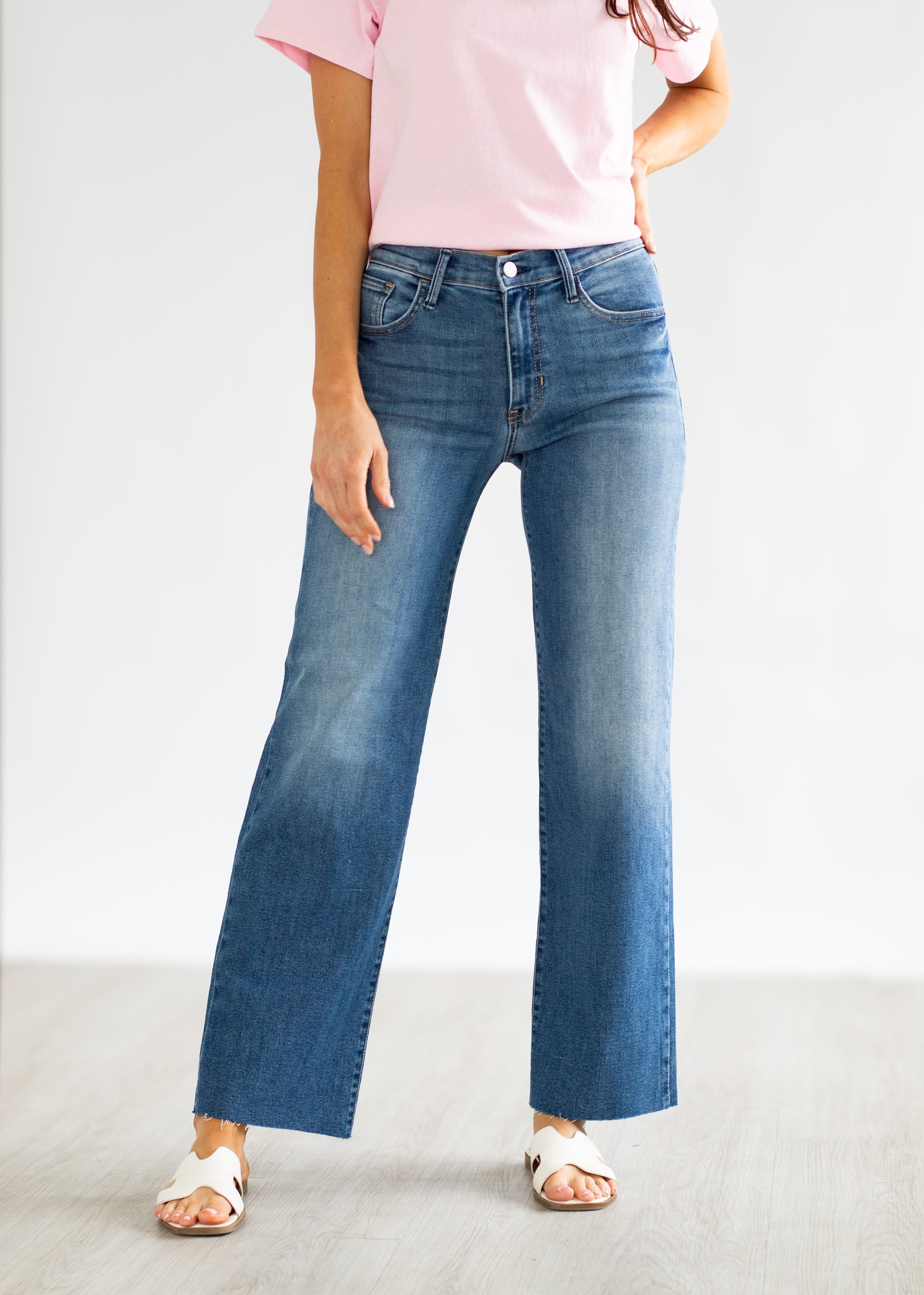 Person wearing blue jeans and a pink shirt on a plain background