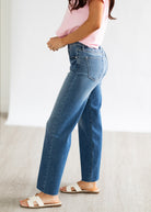 Person wearing blue jeans and a pink top on a plain background