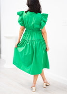 Green dress with ruffled sleeves worn by a person on a white background