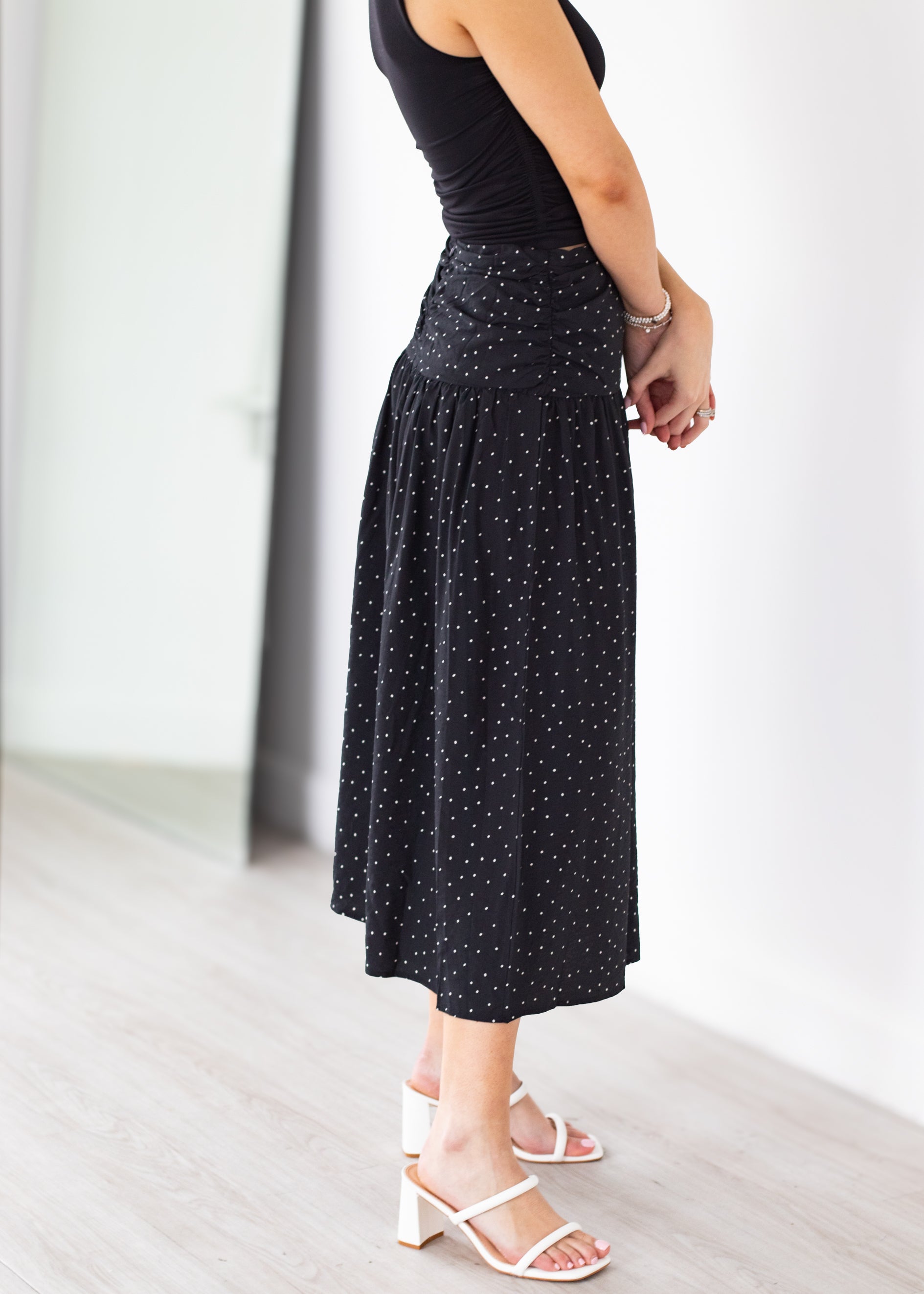 Person wearing a black polka dot skirt with a plain background