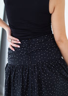 Black sleeveless top and black polka dot skirt worn by a person.