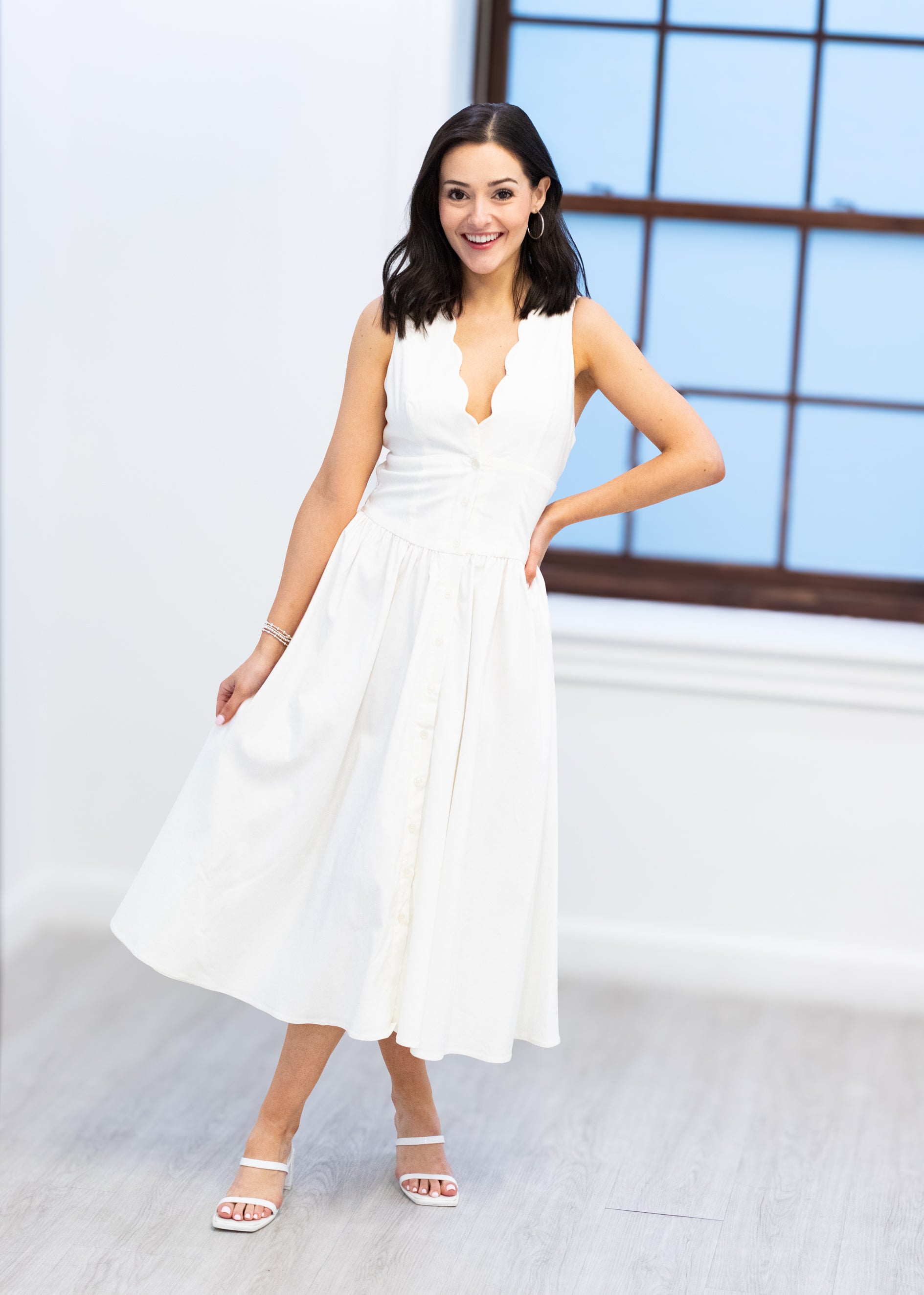 Woman in a white dress standing indoors with a neutral background