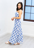 Woman wearing a blue and white checkered dress in a bright room.