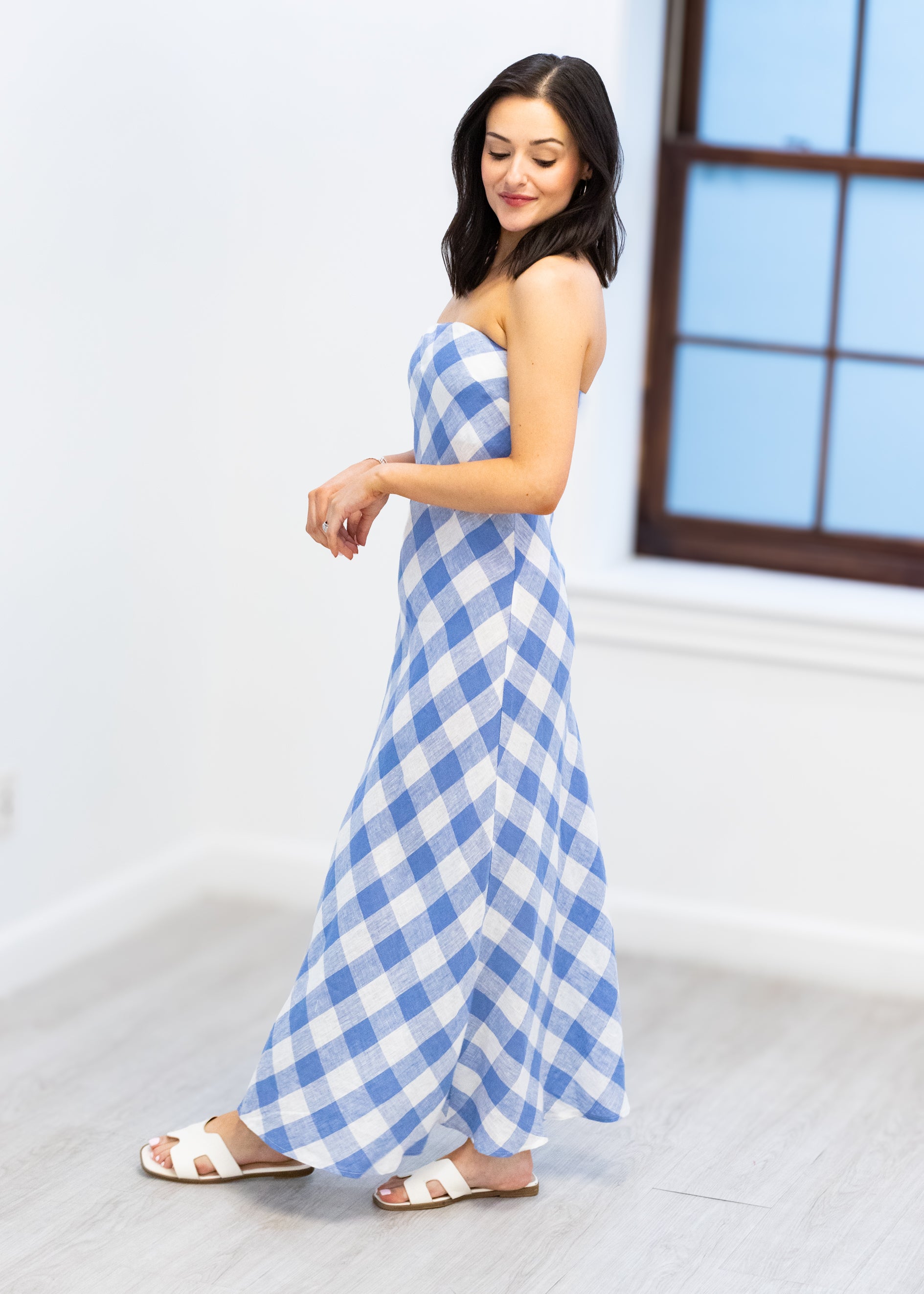 Woman wearing a blue and white checkered dress in a bright room.