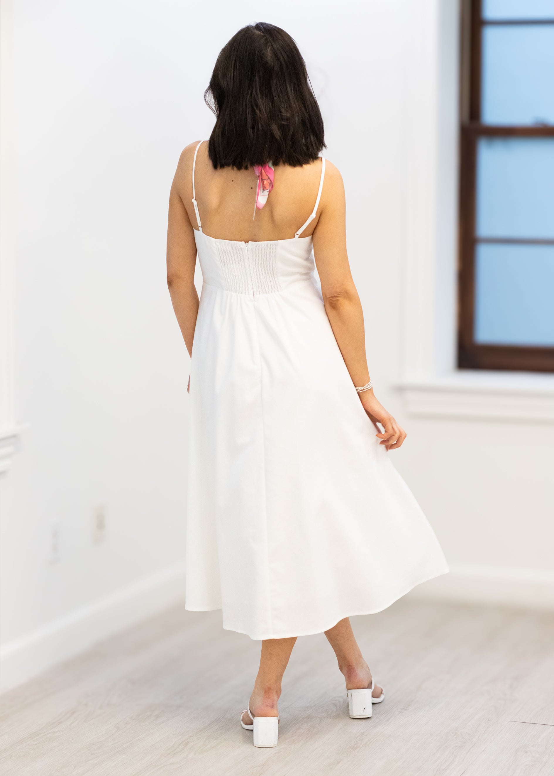 Woman wearing a white dress in a minimal indoor setting