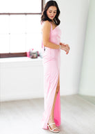 Woman wearing a pink dress with a slit in a minimalistic setting