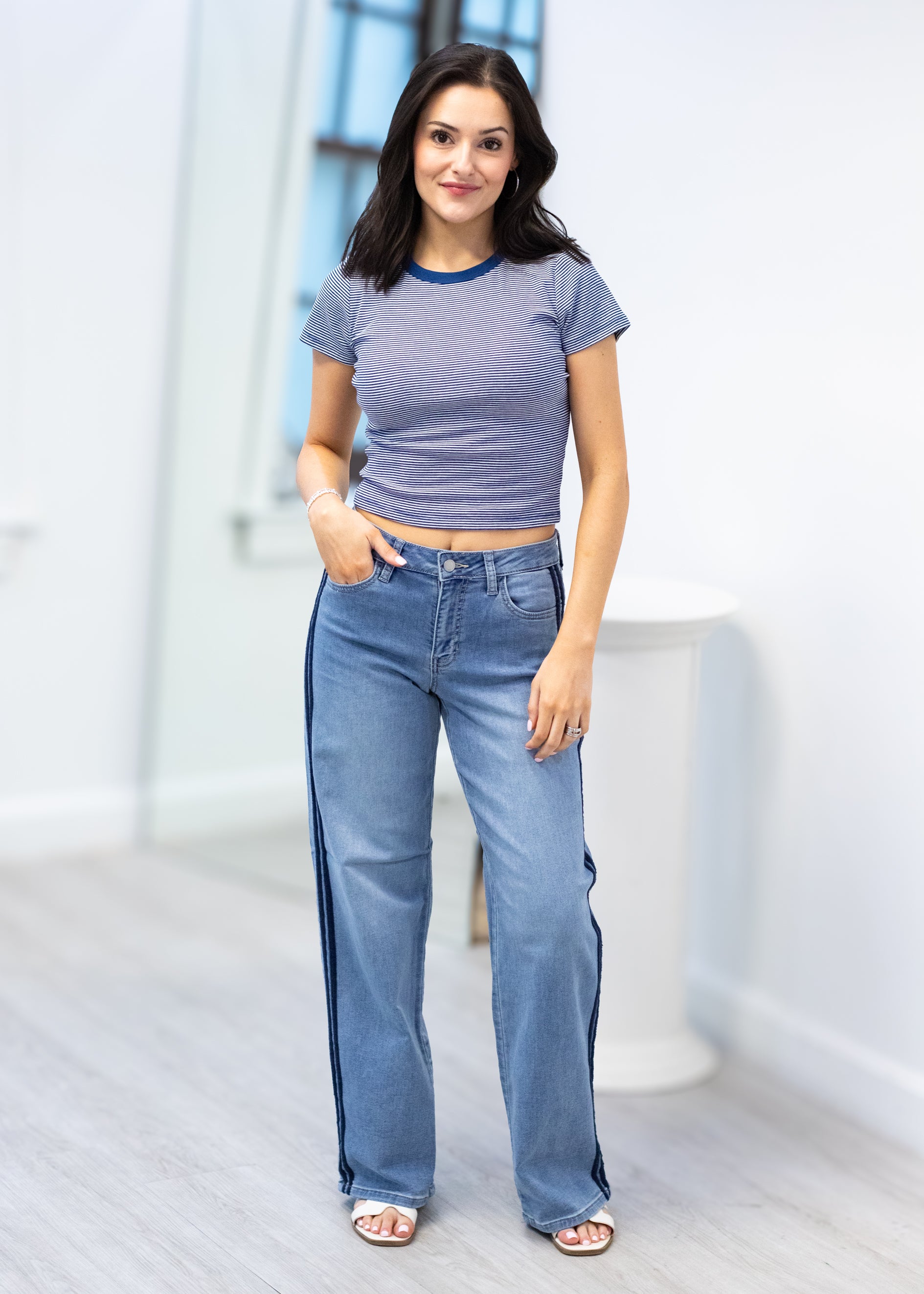 Woman wearing a purple crop top and blue jeans indoors.
