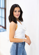 Woman wearing a white top and blue jeans against a white background