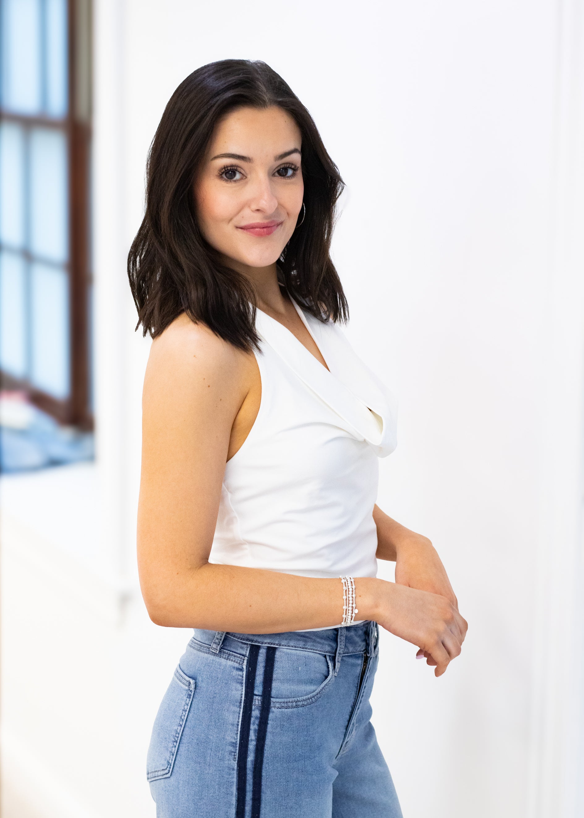 Woman wearing a white top and blue jeans against a white background