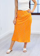 Person wearing an orange polka dot skirt on a white background
