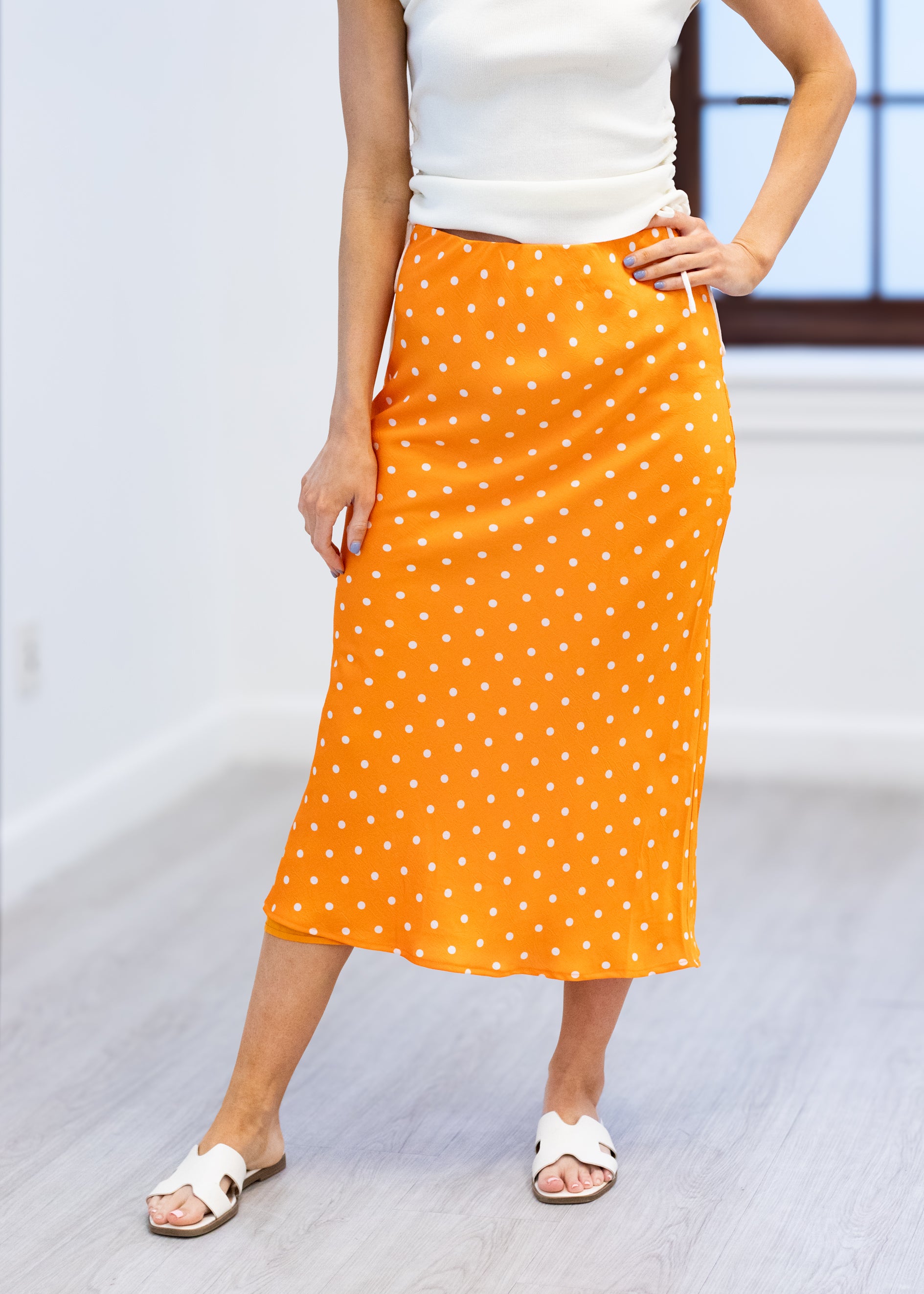 Person wearing an orange polka dot skirt on a white background