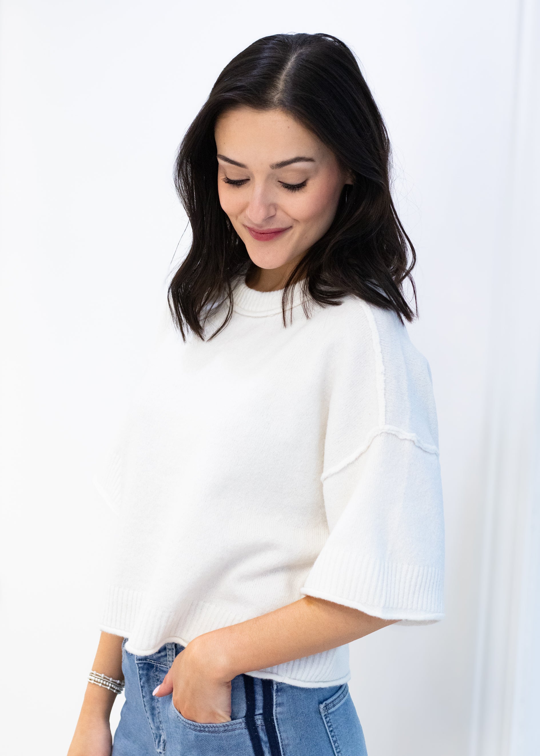 Woman wearing a white blouse with bell sleeves against a plain background