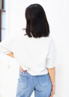 Person wearing a white blouse and blue jeans with a blurred background
