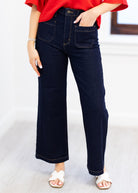 Person wearing dark blue jeans and a red top on a light background