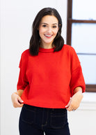 Woman wearing a red sweater in an indoor setting