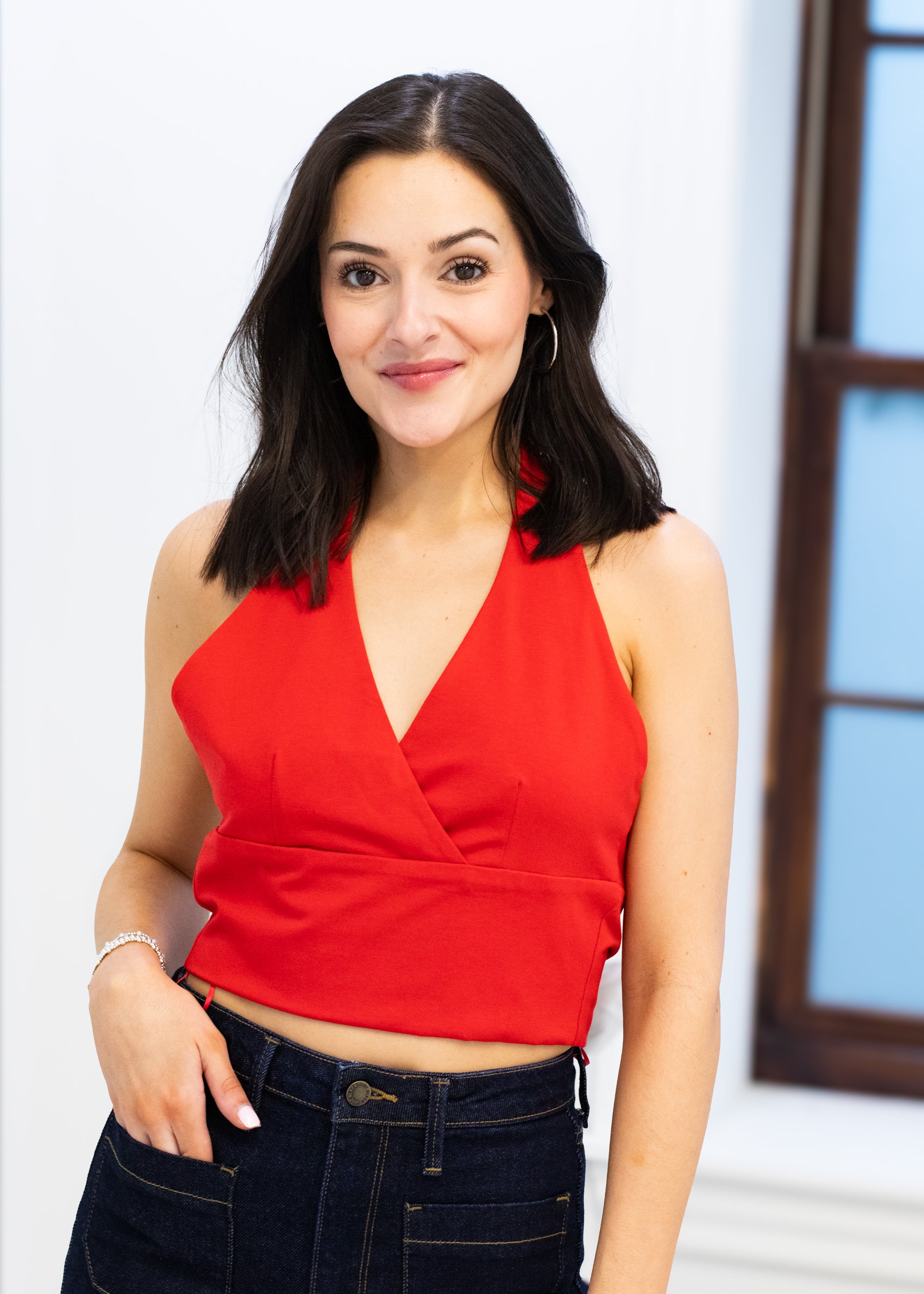 Woman wearing a red top and black pants against a light background