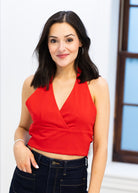Woman wearing a red top and black pants against a light background