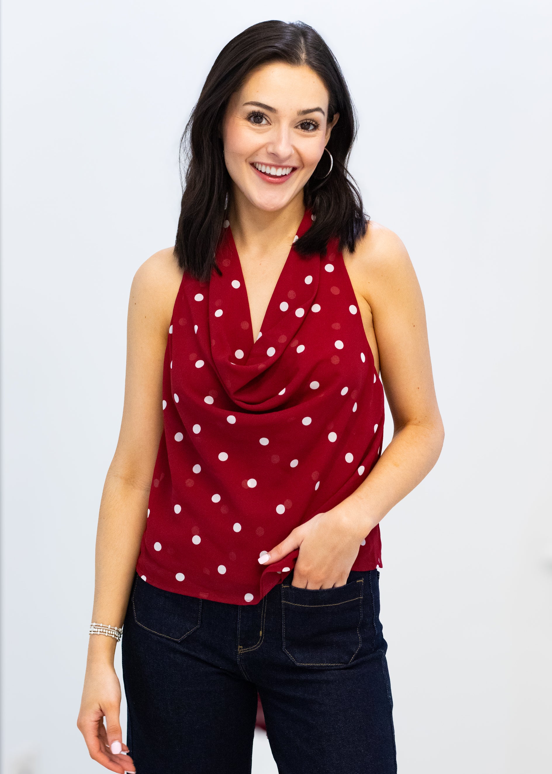 Woman wearing a red polka dot top against a white background